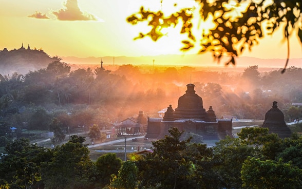 Au soleil couchant, un temple et une maison dans la brume dans l’Etat de Rakhine, au Myanmar. 