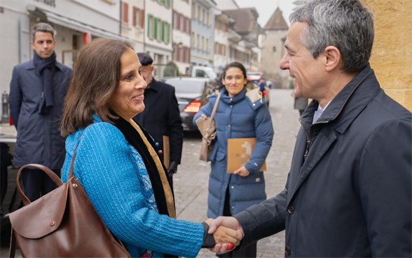 Le conseiller fédéral Cassis et la ministre des affaires étrangères Urrejola Noguera se serrent la main. En arrière-plan, on aperçoit les maisons de Morat.