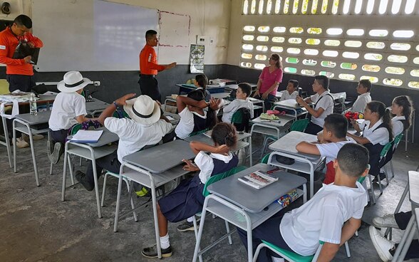 Dans une salle de classe, des experts sensibilisent les élèves aux risques liés aux mines.