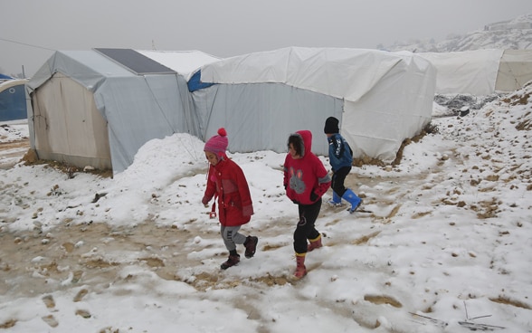 Des enfants marchent dans la neige dans un camp de déplacés internes.