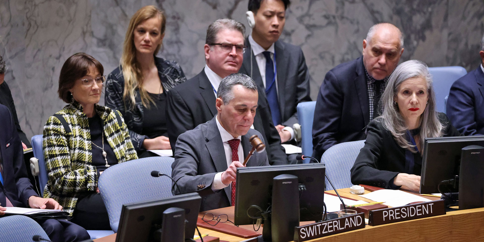 Le conseiller fédéral Ignazio Cassis est assis à la table en fer à cheval du Conseil de sécurité de l'ONU. Devant lui se trouve un panneau en bois portant l'inscription «Président».