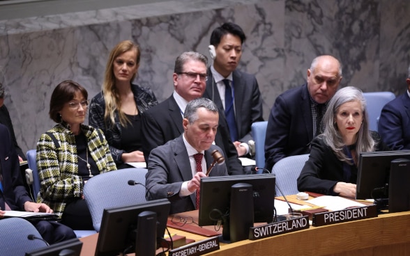 Il consigliere federale Ignazio Cassis siede al tavolo a ferro di cavallo del Consiglio di sicurezza dell'ONU e batte con un martello di legno.