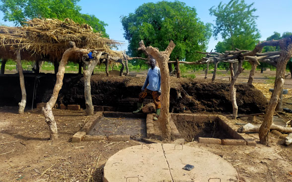 Un contadino del Burkina Faso si trova accanto a un cumulo di compost.