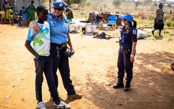 Eine Polizistin der UNO-Polizei spricht mit einem afrikanischen Jungen.