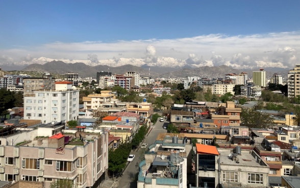 Ansicht der Stadt Kabul von oben mit weissem Gebirge im Hintergrund.