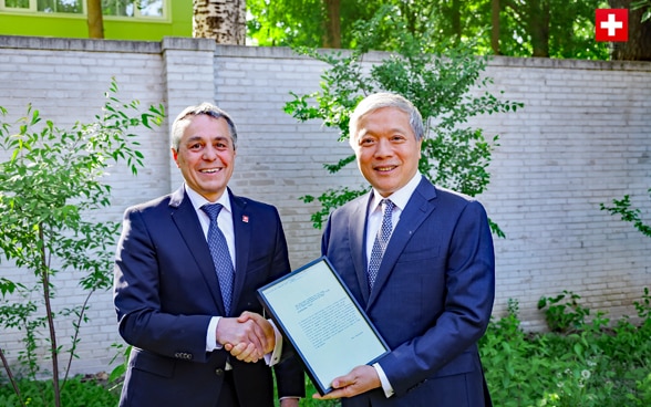 Le conseiller fédéral Ignazio Cassis et l'ambassadeur Zhu Liying se serrent la main. 