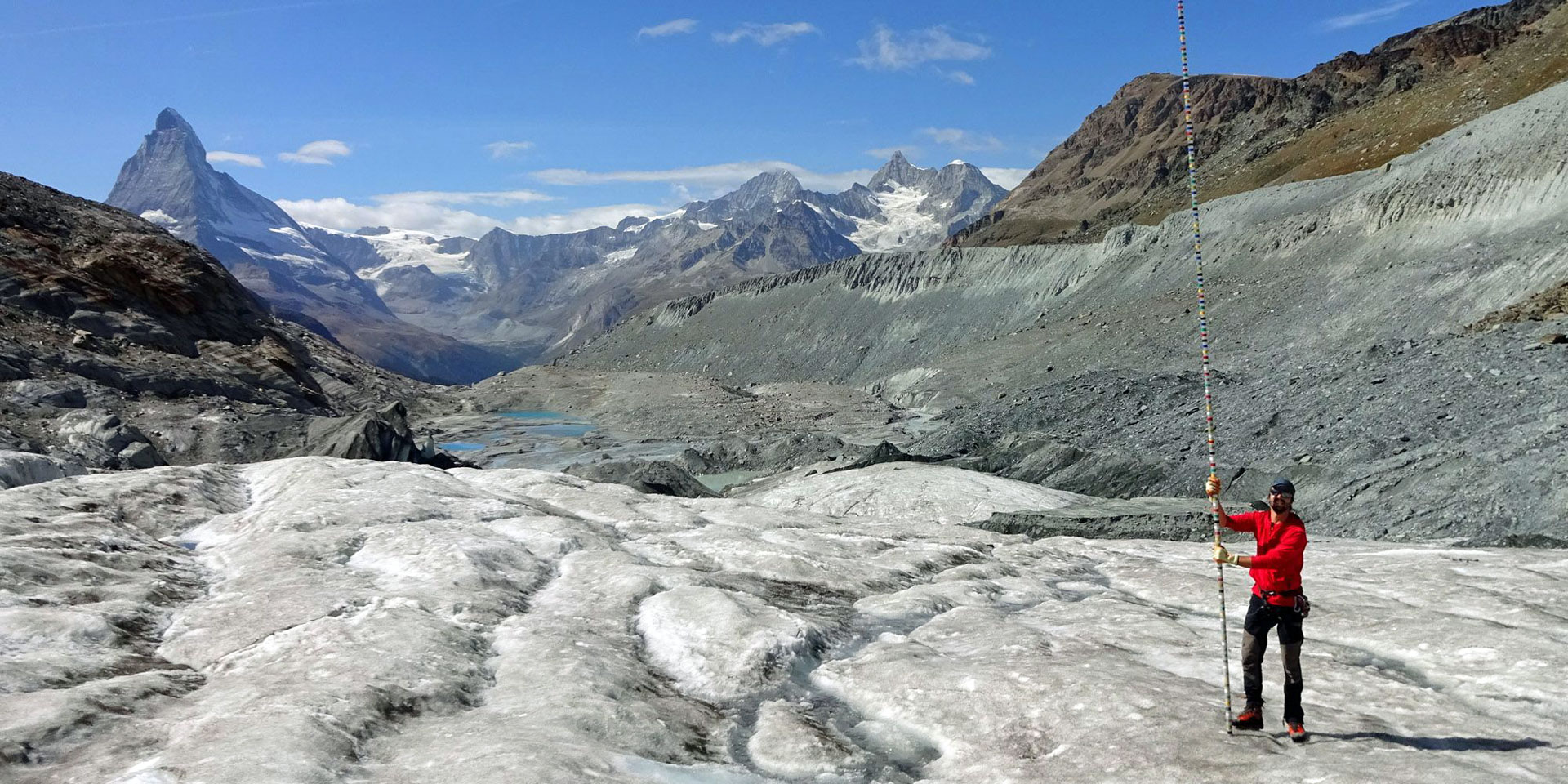 Ein Mann mit einer Messstange auf einem Gletscher in den Schweizer Alpen.