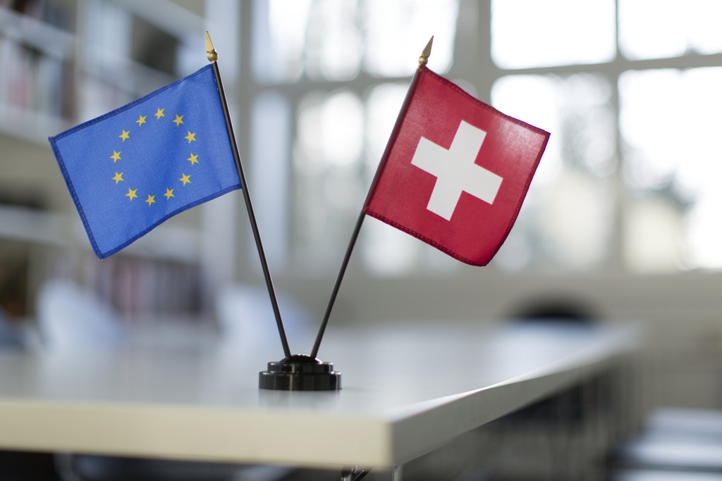 The Swiss and EU flags standing on a white table.