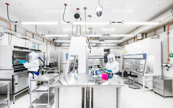 Two employees in protective clothing at work in the Spiez biocontainment laboratory.