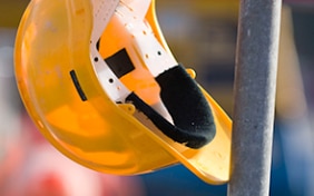 Un casco giallo appeso all' impalcatura di un cantiere.