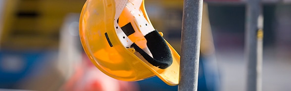 Un casco giallo appeso all' impalcatura di un cantiere.