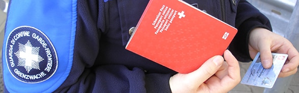 A border guard checks a Swiss passport and ID card