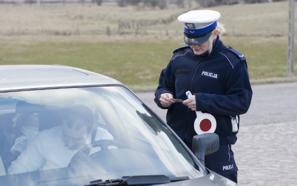 A police officer checks a driver's licence.
