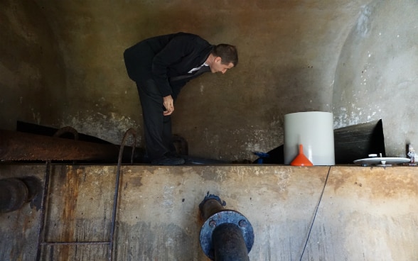 Un uomo è in piedi su un muro e guarda il serbatoio di acqua potabile sotto di lui.