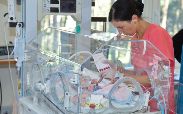 Une aide-soignante s’occupe d’un nouveau-né placé dans une couveuse.
