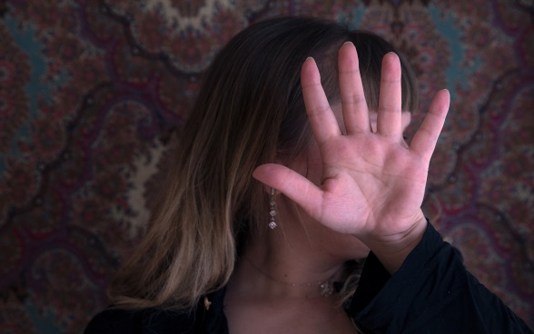 Une victime de la traite des êtres humains se cachant le visage avec sa main.