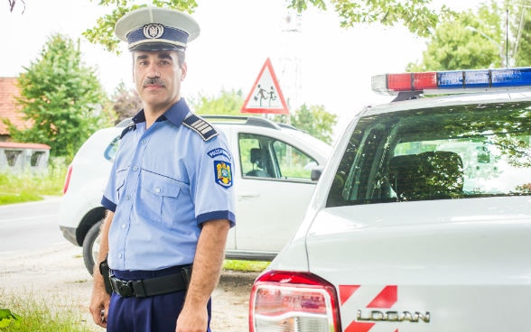 A policeman stands next to a car. 