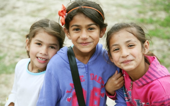 La photo montre trois petites filles souriantes.