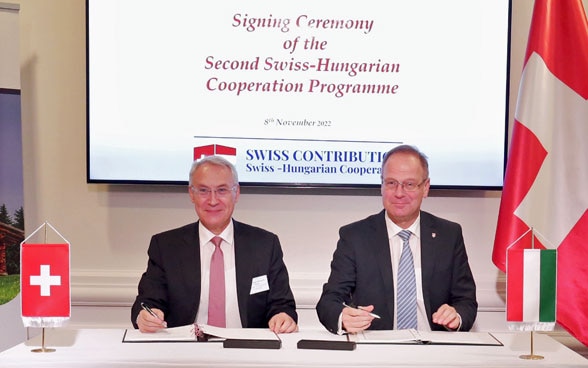 L’8 novembre 2022, a Budapest, l’ambasciatore svizzero Jean-François Paroz e il ministro ungherese dello sviluppo regionale Tibor Navracsics firmano l’accordo quadro relativo al nuovo programma di cooperazione tra la Svizzera e l’Ungheria.
