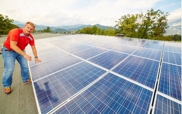 Un jeune homme se tient à côté de panneaux photovoltaïques.