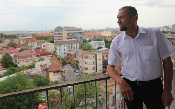 Francisc Giurgiu, Vorsitzender des Vereins Opération Villages Roumains - Suisse auf rumänischer Seite, auf einem Balkon.
