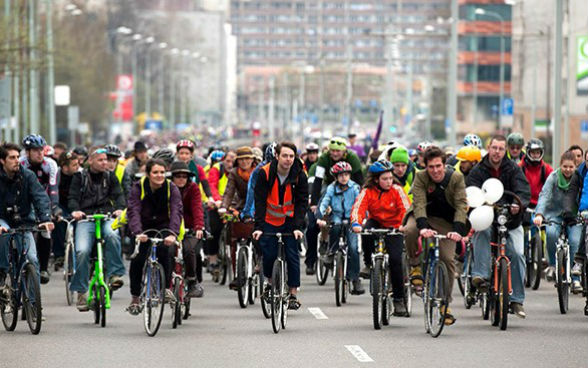 Des cyclistes circulent en groupe sur toute la largeur d’une rue.