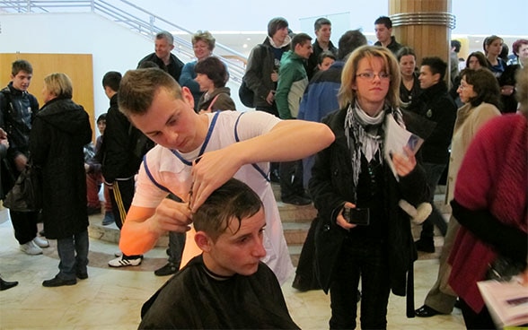 An apprentice cuts another apprentice’s hair.