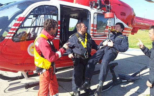 Zwei Rettungskräfte sind mit einem Helikopter in der Luft bei einer Rettungsaktion im Einsatz.  